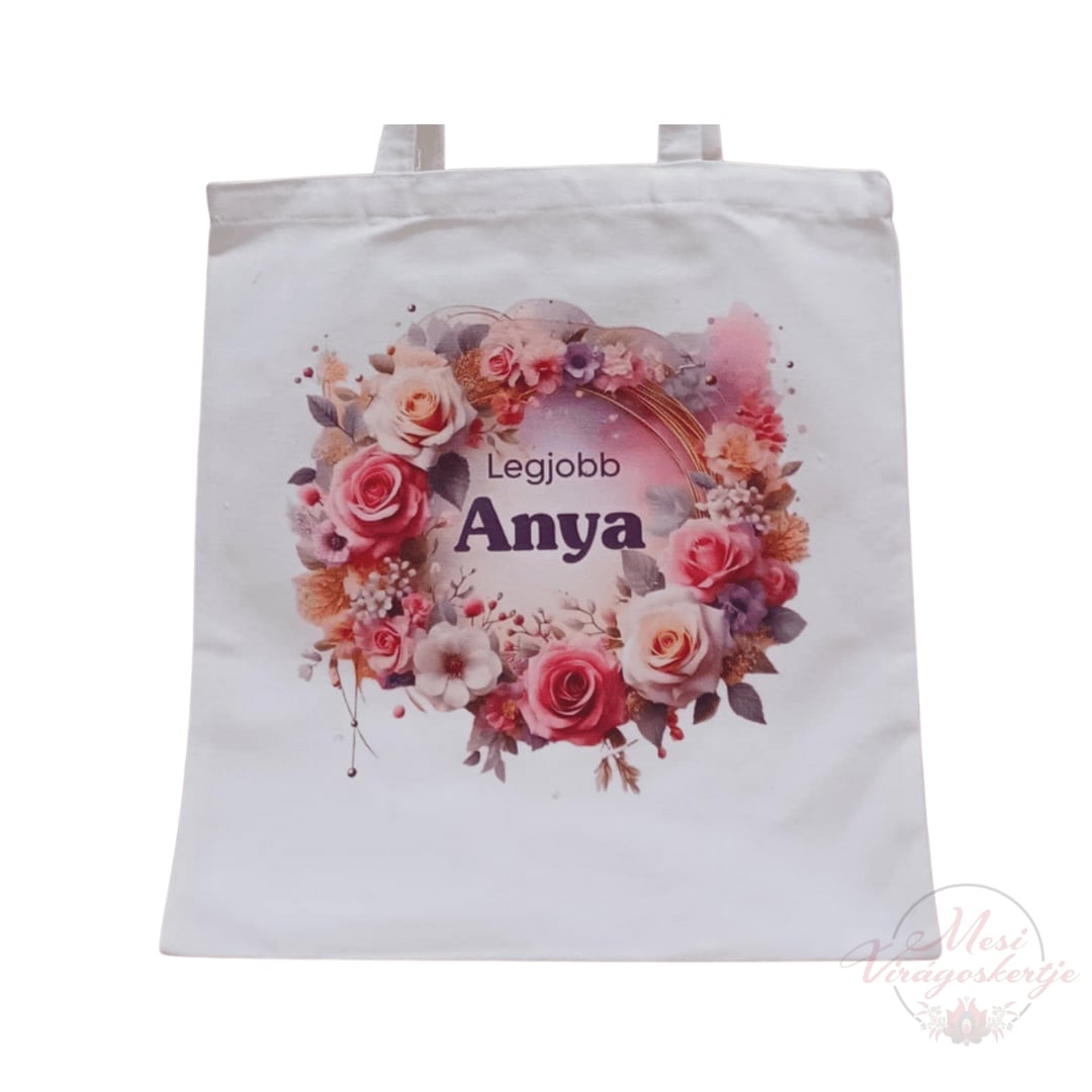 Fehér vászontáska két füllel, elején színes virágkoszorúval és „Legjobb Anya” felirattal.