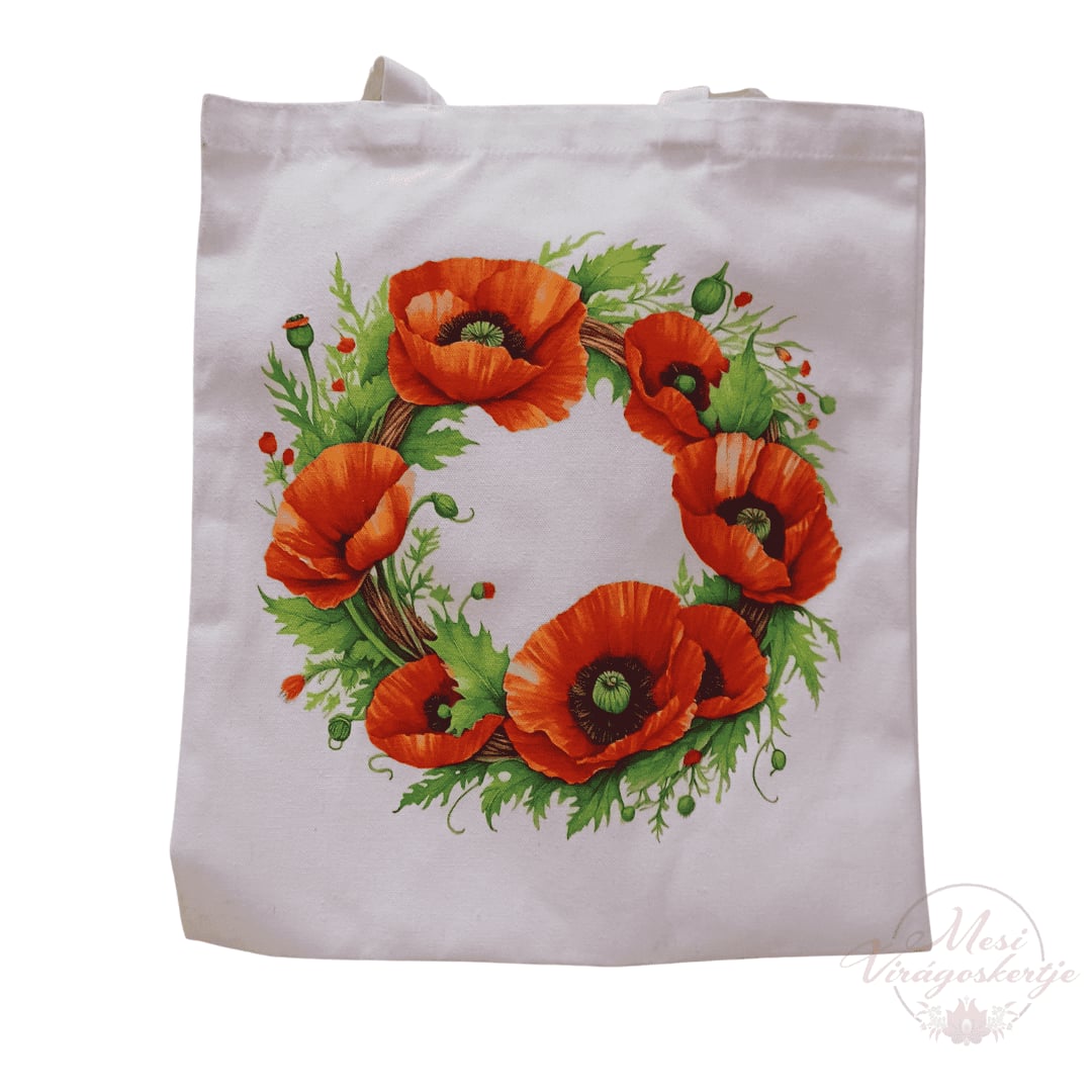 Fehér vászontáska, rajta piros pipacsokból és zöld levelekből álló koszorúmintával, alul „Mesé Virágoskertje” vízjellel.